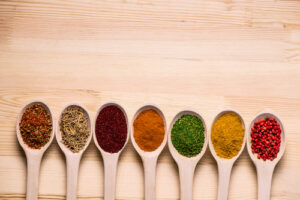 Spices in spoons on wooden table